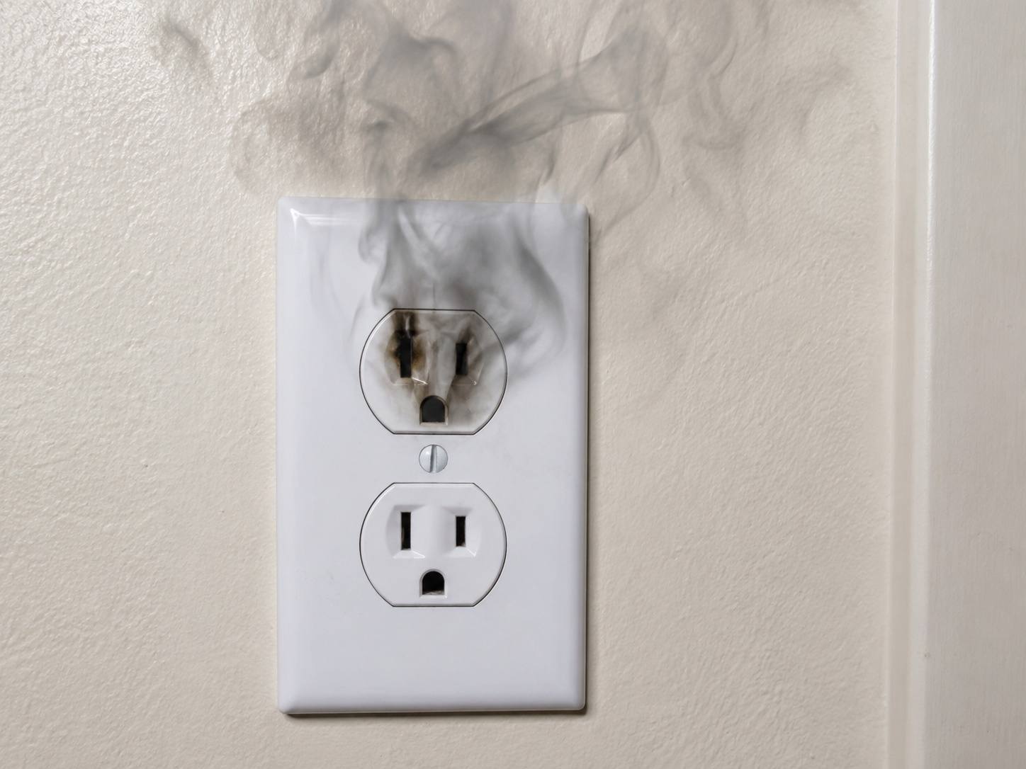 Zadimljena električna utičnica sa tragovima pregorevanja.